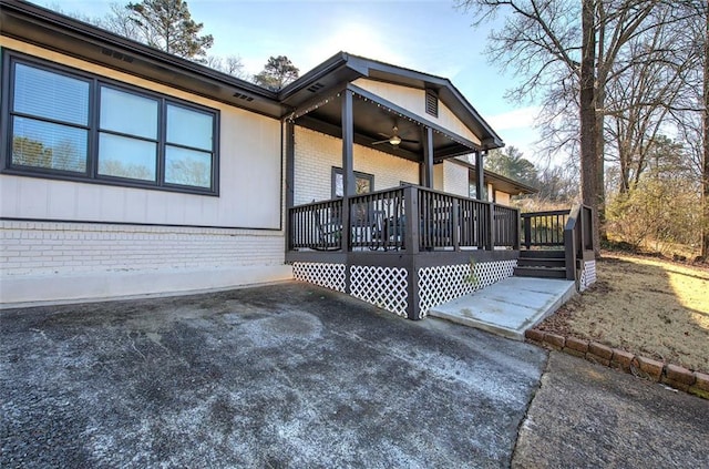 view of property exterior featuring a patio area, brick siding, ceiling fan, and a deck