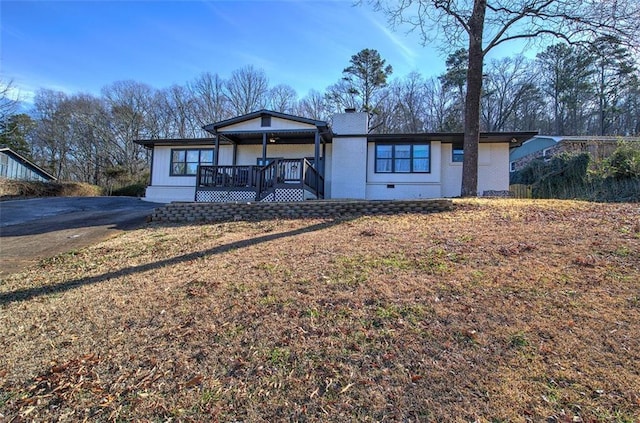 view of front facade featuring driveway, a chimney, and a front yard