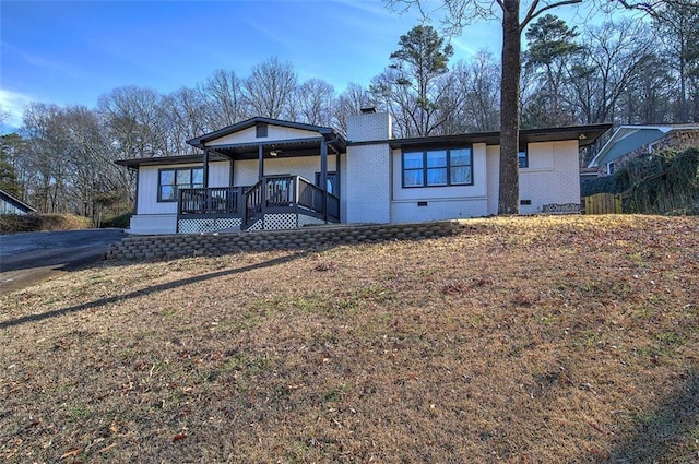 view of front of home with a chimney, crawl space, a yard, a porch, and brick siding