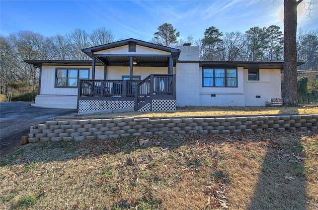 view of front facade featuring crawl space, brick siding, a chimney, and covered porch