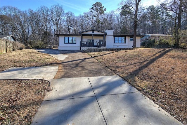 view of front of house featuring covered porch, fence, and concrete driveway