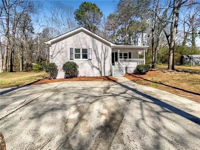 view of front facade with driveway, covered porch, and a front lawn