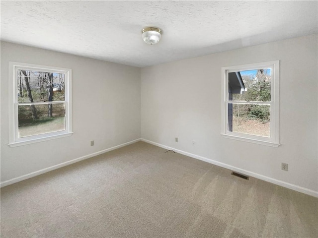 unfurnished room featuring carpet, visible vents, baseboards, and a textured ceiling