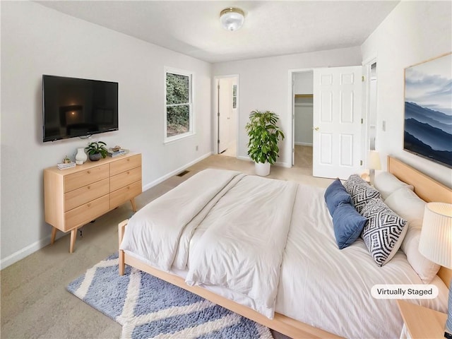 bedroom with baseboards, a spacious closet, visible vents, and light colored carpet