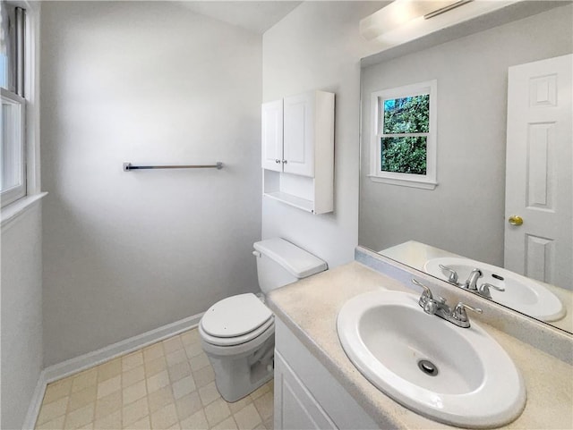 bathroom featuring toilet, baseboards, and vanity