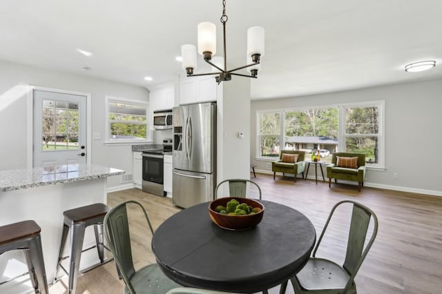 2519 Miriam Ln, Decatur, GA 30032 - dining area featuring baseboards, a healthy amount of sunlight, a chandelier, and light wood-type flooring