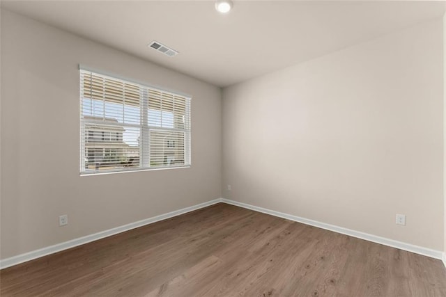 empty room featuring visible vents, baseboards, and wood finished floors