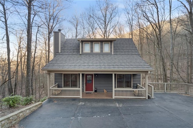 rustic home featuring covered porch and a chimney