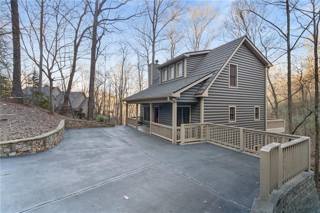 view of side of home featuring a chimney and roof with shingles