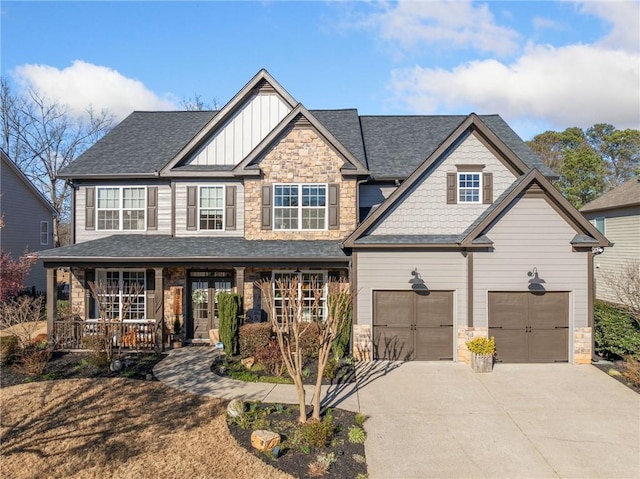 craftsman-style home featuring covered porch, a garage, driveway, stone siding, and board and batten siding