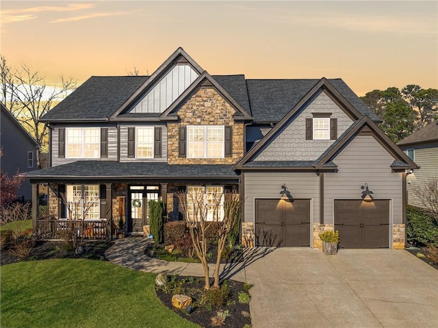 craftsman-style house with covered porch, concrete driveway, stone siding, board and batten siding, and a front yard