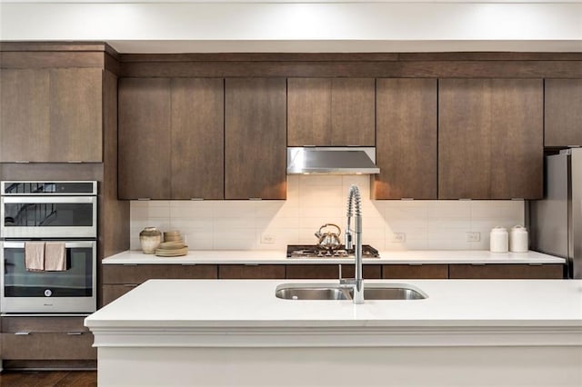 kitchen featuring stainless steel double oven, dark brown cabinetry, and dark wood-type flooring