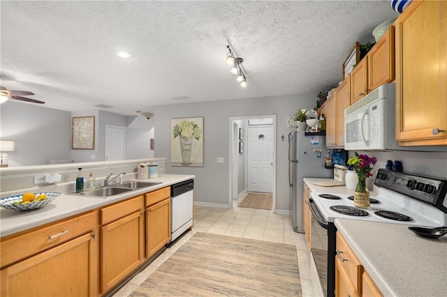 kitchen with electric range, white microwave, dishwashing machine, a sink, and light countertops