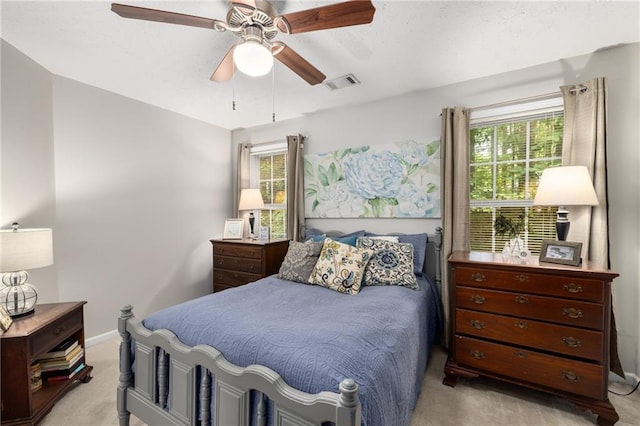 bedroom featuring light colored carpet, multiple windows, baseboards, and ceiling fan