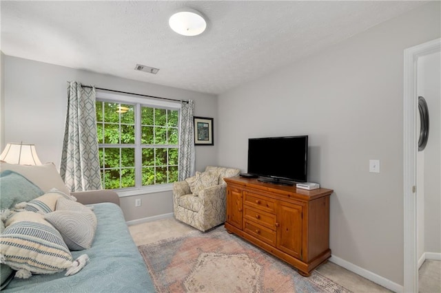 living room with light carpet, baseboards, and a textured ceiling