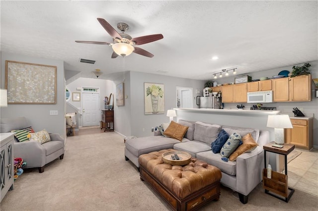 living area with light colored carpet, a ceiling fan, and a textured ceiling