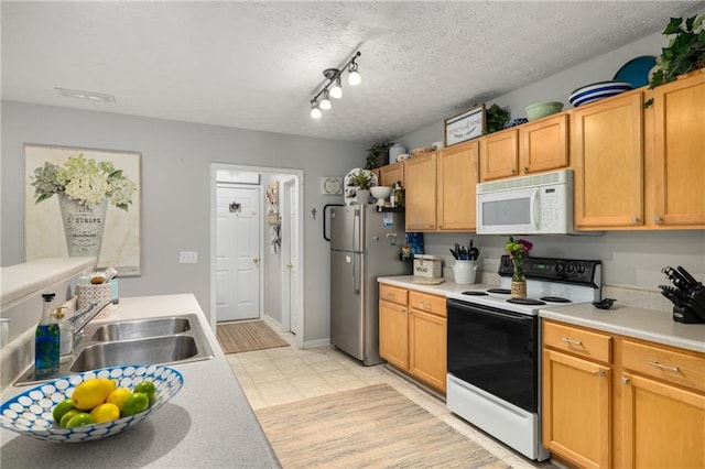 kitchen featuring electric stove, white microwave, freestanding refrigerator, light countertops, and a sink