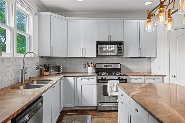 1622 Gates Pl NW, Atlanta, GA 30318 - kitchen featuring appliances with stainless steel finishes, light stone countertops, dark wood-type flooring, crown molding, and tasteful backsplash