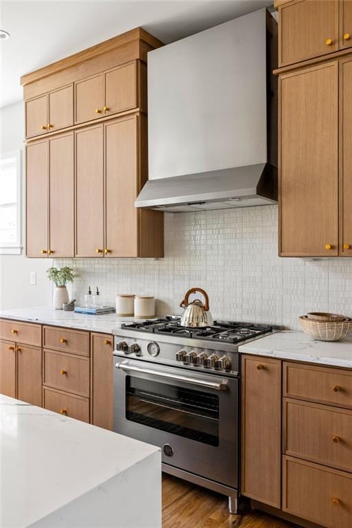 kitchen featuring stainless steel range, light hardwood / wood-style floors, tasteful backsplash, and wall chimney range hood