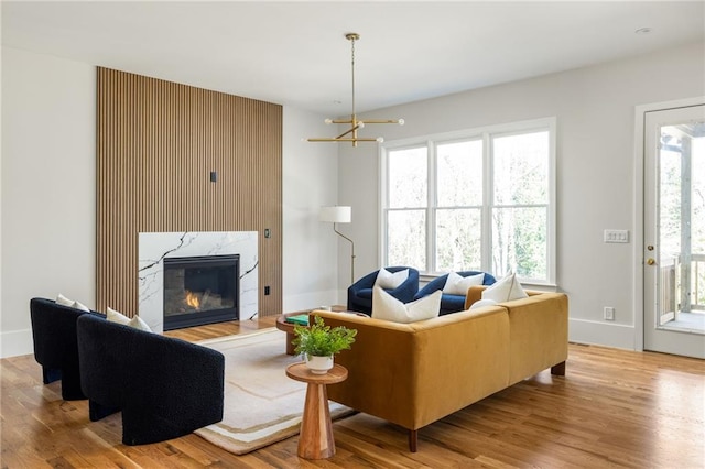 living room featuring light wood-type flooring, a high end fireplace, and an inviting chandelier