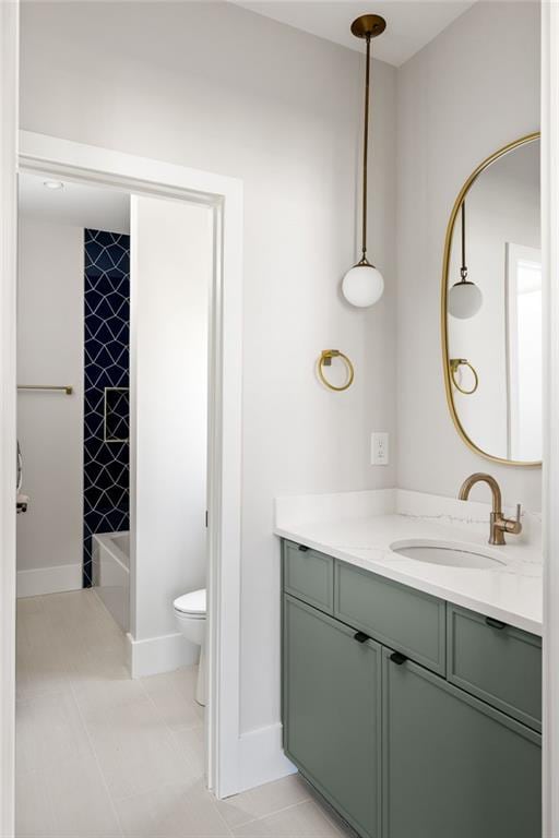 full bathroom with toilet, tile patterned flooring, tiled shower / bath combo, and vanity