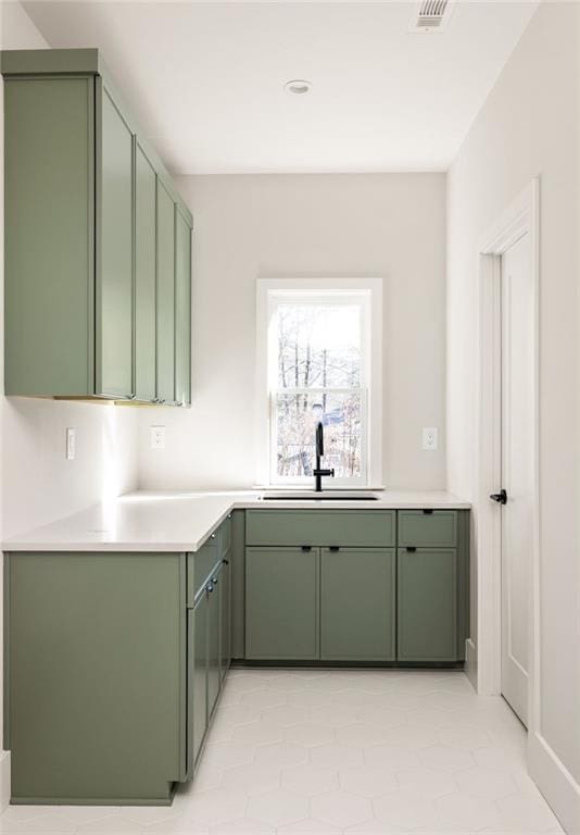 kitchen with light tile patterned floors, sink, and green cabinets