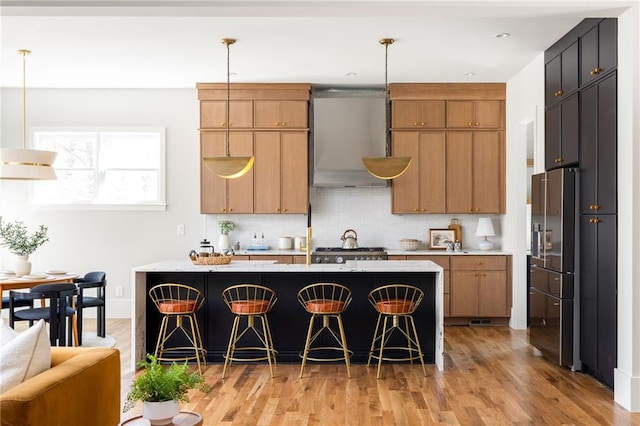 kitchen featuring pendant lighting, exhaust hood, and an island with sink