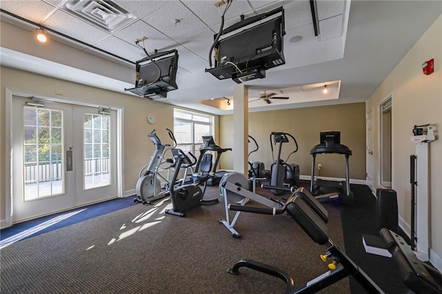 gym with a paneled ceiling, a raised ceiling, and french doors