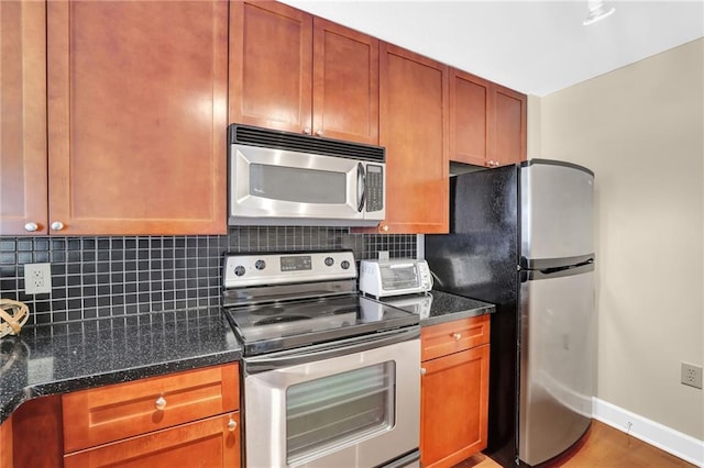 kitchen featuring dark stone counters, backsplash, appliances with stainless steel finishes, and hardwood / wood-style flooring