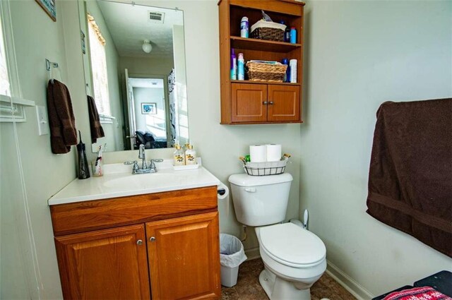 bathroom with visible vents, vanity, toilet, and baseboards