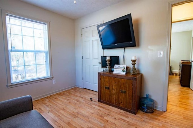 living room with a textured ceiling, light wood finished floors, and baseboards