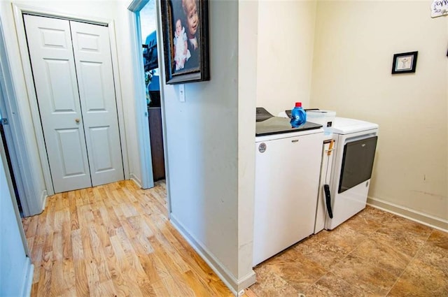 laundry area with laundry area, light wood-style floors, washer and clothes dryer, and baseboards