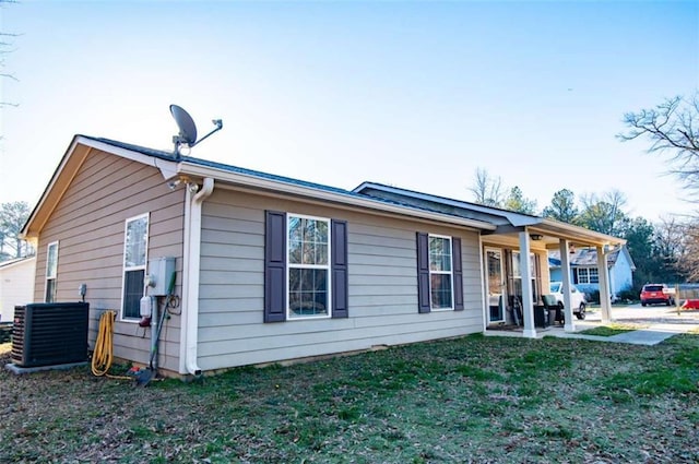 view of front of house with central air condition unit, a patio area, and a front yard