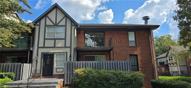 view of front of house with brick siding, fence, and stucco siding