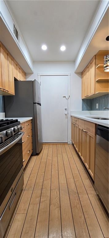 kitchen featuring light brown cabinets, stainless steel appliances, sink, pendant lighting, and light hardwood / wood-style flooring