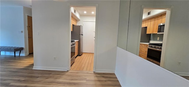 kitchen with appliances with stainless steel finishes, wood finished floors, baseboards, and recessed lighting