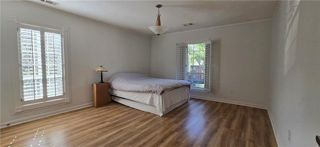 bedroom with wood finished floors, ornamental molding, and baseboards