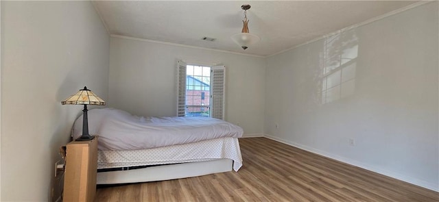 bedroom featuring ornamental molding, wood finished floors, and baseboards