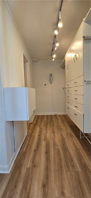 empty room featuring track lighting, wood finished floors, and baseboards