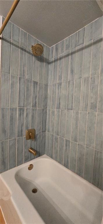 bathroom featuring a textured ceiling and tiled shower / bath combo