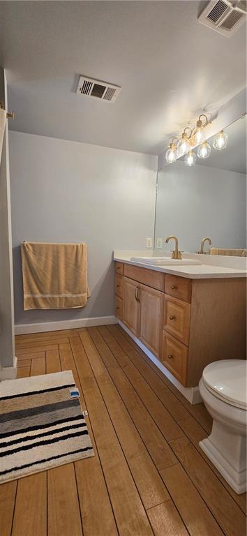 bathroom with hardwood / wood-style floors, vanity, toilet, and baseboards