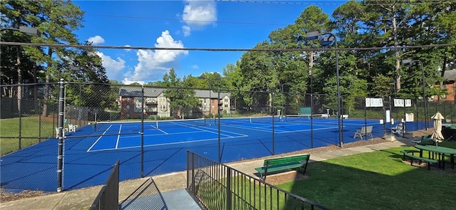 view of tennis court featuring a yard