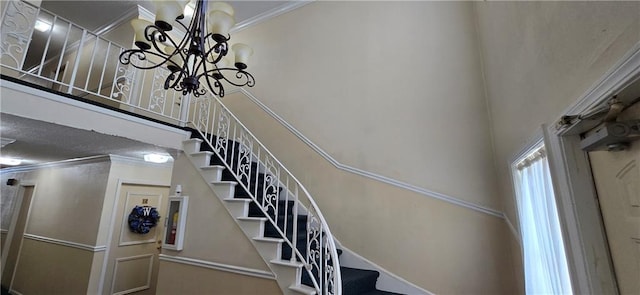 stairway featuring a chandelier, crown molding, and a high ceiling
