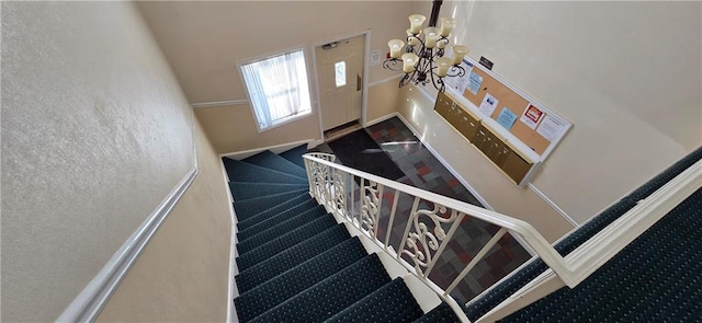 stairway featuring a chandelier, carpet, and a towering ceiling