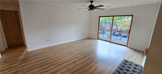 empty room with wood finished floors, a ceiling fan, and baseboards