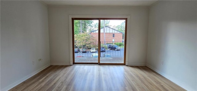 spare room featuring ornamental molding and light hardwood / wood-style floors