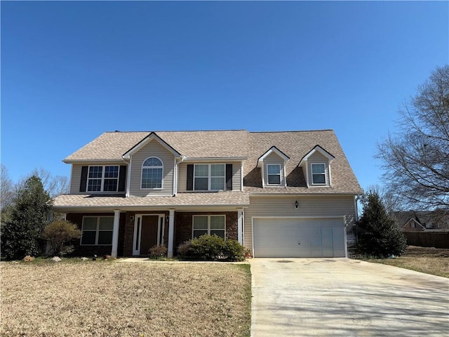 view of front facade with a front lawn, concrete driveway, roof with shingles, and an attached garage