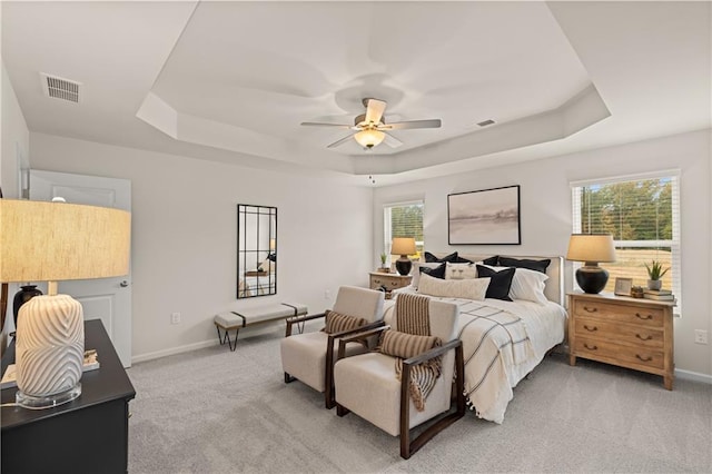 bedroom featuring a tray ceiling, visible vents, and light carpet