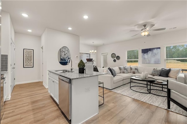 kitchen featuring a sink, white cabinets, open floor plan, light wood-type flooring, and dishwasher