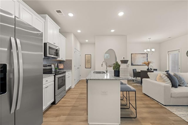 kitchen with white cabinets, light wood-style flooring, appliances with stainless steel finishes, a breakfast bar, and a sink